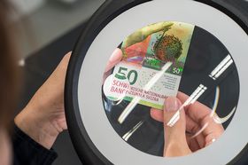 Prüfung einer druckfrischen 50-Franken-Note mit der Lupe