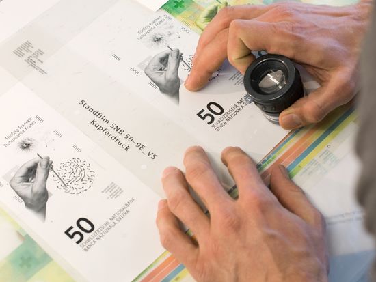 Graphiste examinant attentivement le recto d&#039;un billet